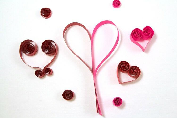 quilled red and pink paper hearts and swirls on white background