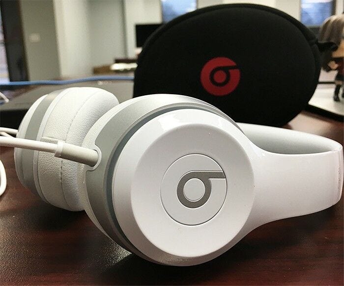 white and silver beats headphones with black and red beats headphone case on desk