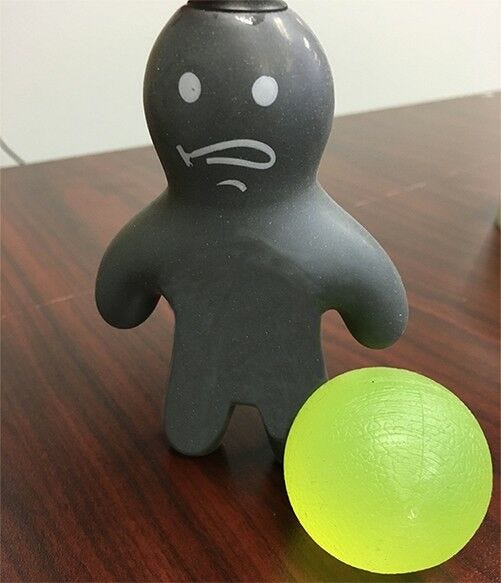 gray human shaped stress toy and green transparent stress ball in stress free office space