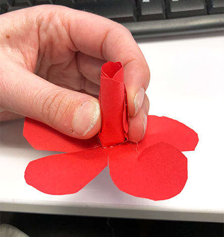 hand holding red paper rose craft by rolled up paper bud