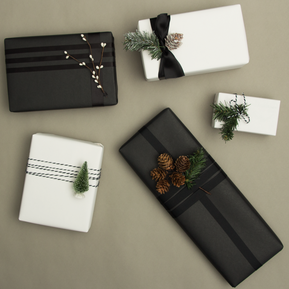 holiday wrapping trend 1: 5 black and white wrapped presents with pine cone decorations.