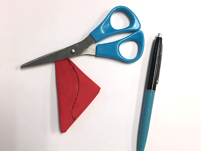 folded red napkin with drawn black line, blue scissors, black ballpoint pen