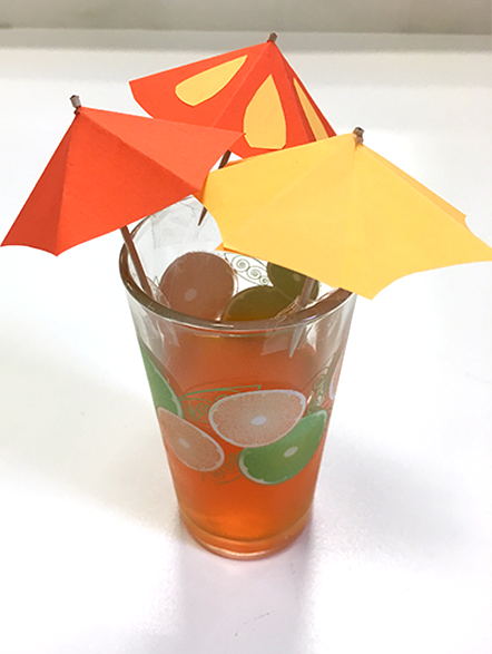 glass cup with orange drink and orange themed drink umbrellas