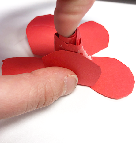 hand gluing red paper rose petals to center bud