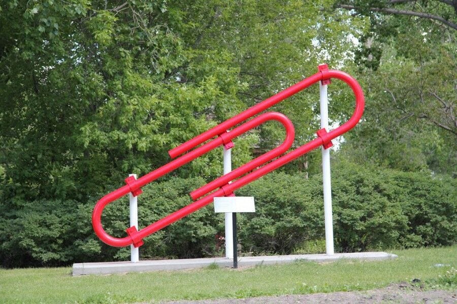 large red paper clip office supply statue in park with trees