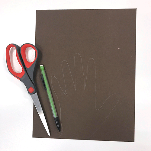 pair of scissors and lead pencil on top of brown paper with hand tracing